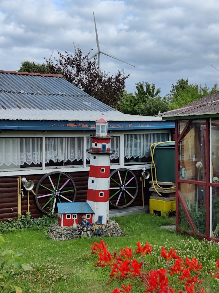 A whimsical garden with a lighthouse model and vibrant flowers in Hamburg, Germany.